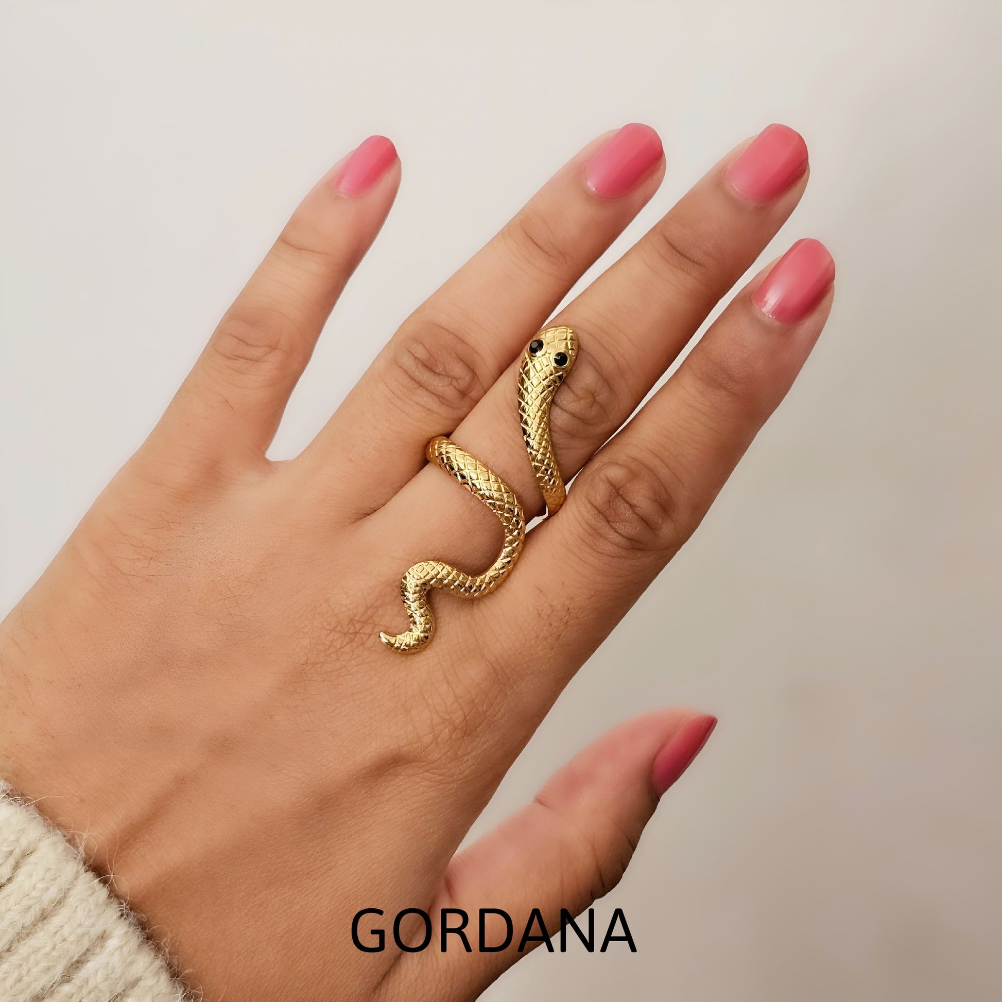 Gold snake-shaped ring on a hand with pink nail polish - stainless steel jewelry shipping worldwide from Mauritius