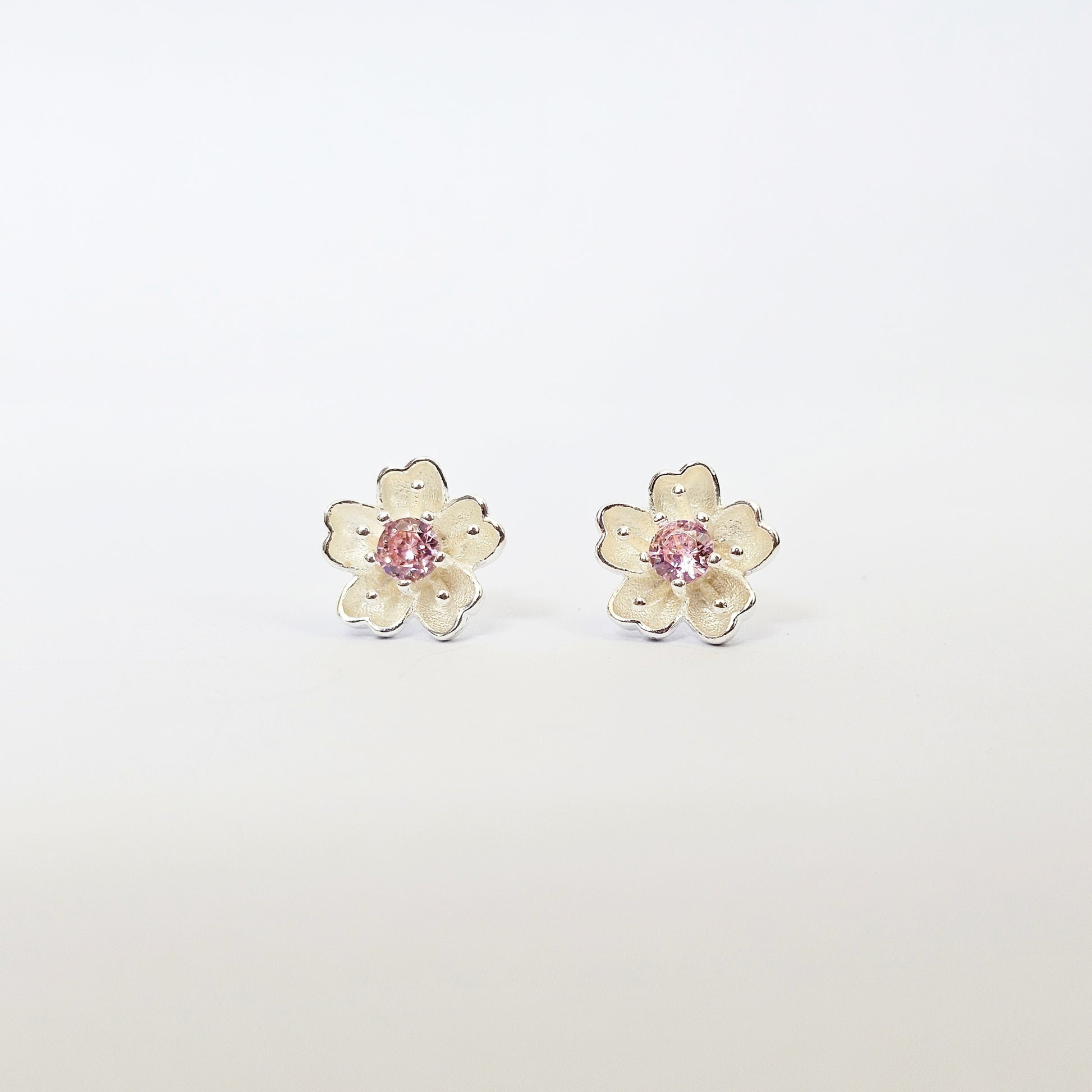 Silver jewelry flower stud earrings with pink gemstone centers, stainless steel fashion jewelry for unisex style.