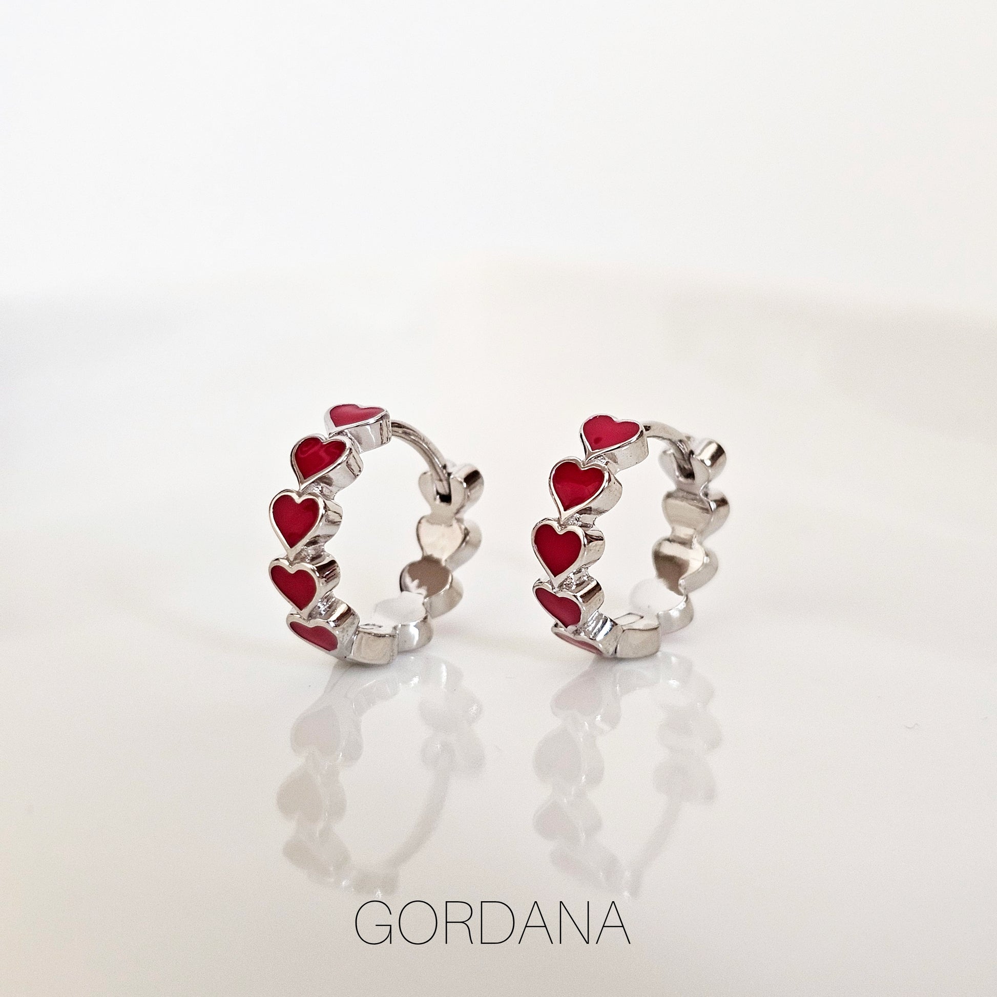 Silver hoop earrings featuring red and silver heart-shaped accents, stainless steel jewelry with a fashionable unisex design .