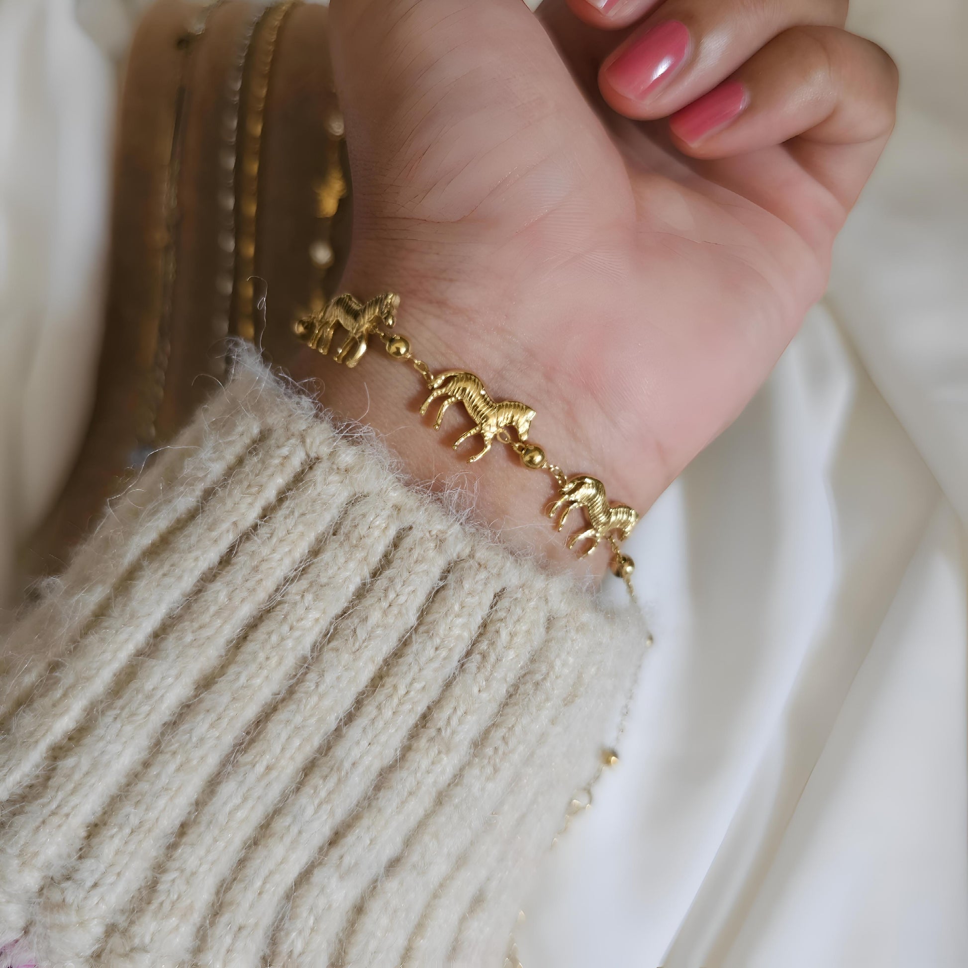 Gold bracelet on a wrist with a neutral background