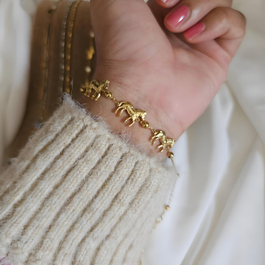 Gold bracelet on a wrist with a neutral background