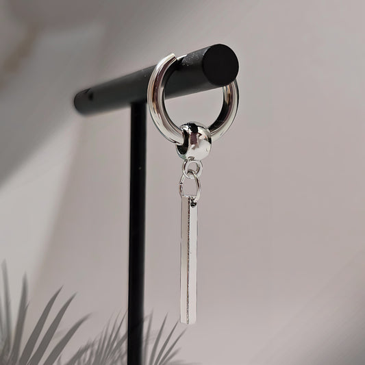 Silver earring with a dangling bar on a black stand against a neutral background