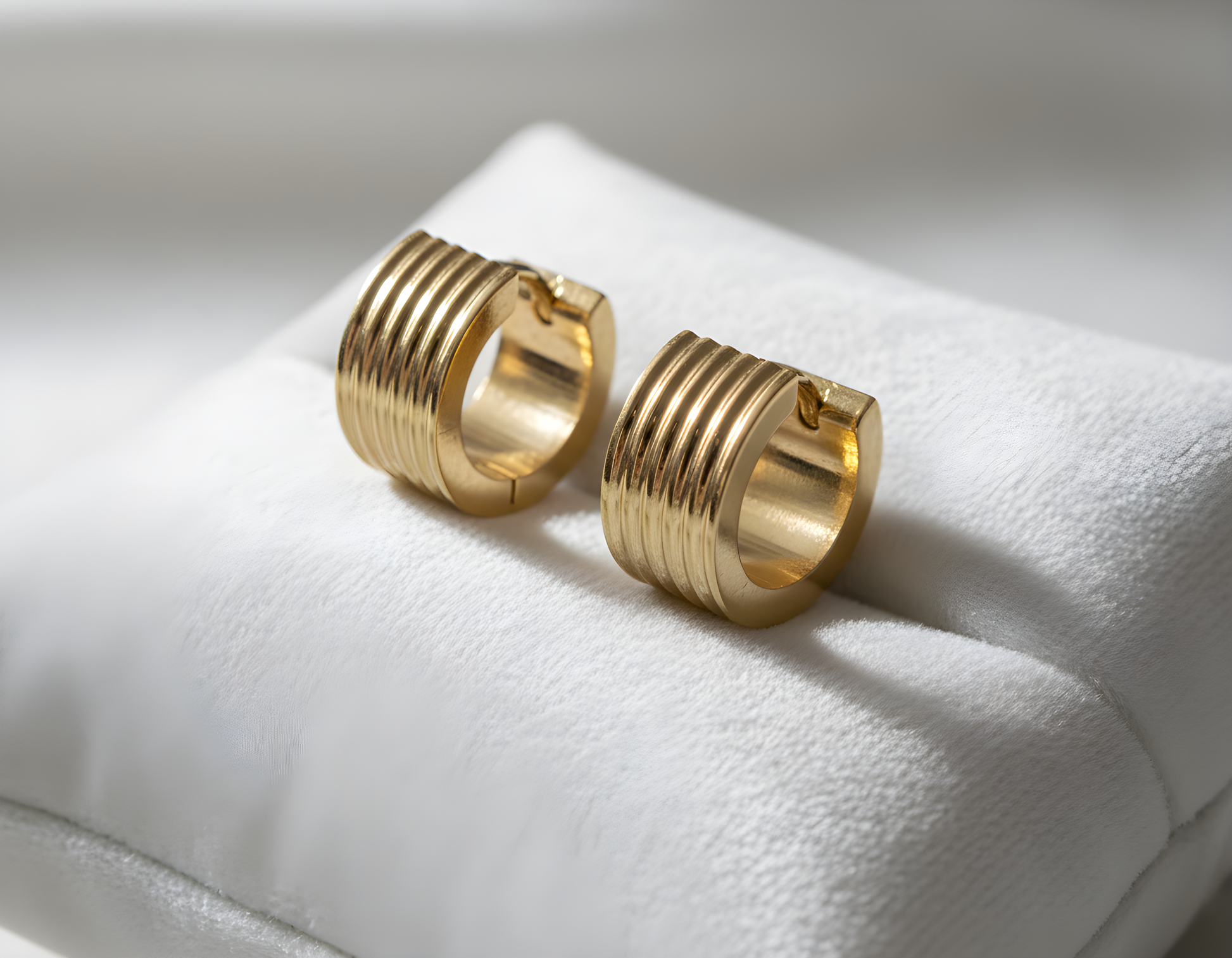 Pair of gold hoop earrings on a white cushion