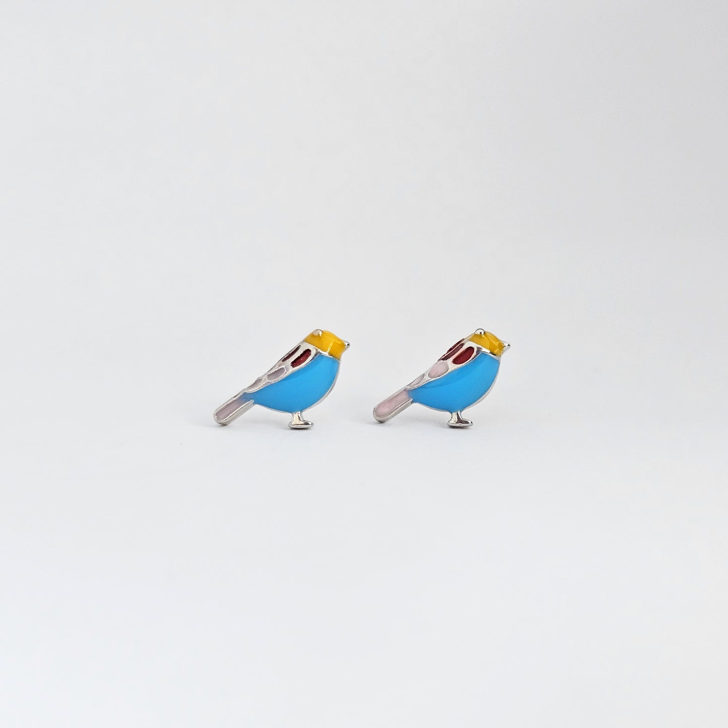 Silver stud earrings shaped like birds with blue and yellow accents, stainless steel jewelry, unisex fashion jewelry.