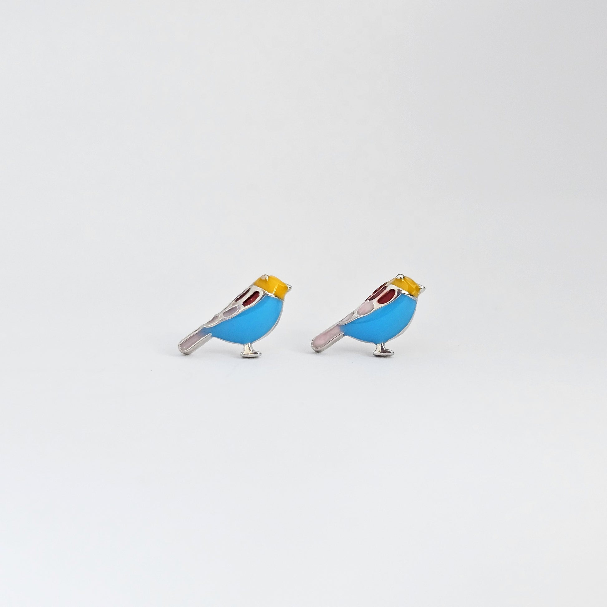 Silver stud earrings shaped like birds with blue and yellow accents, stainless steel jewelry, unisex fashion jewelry.