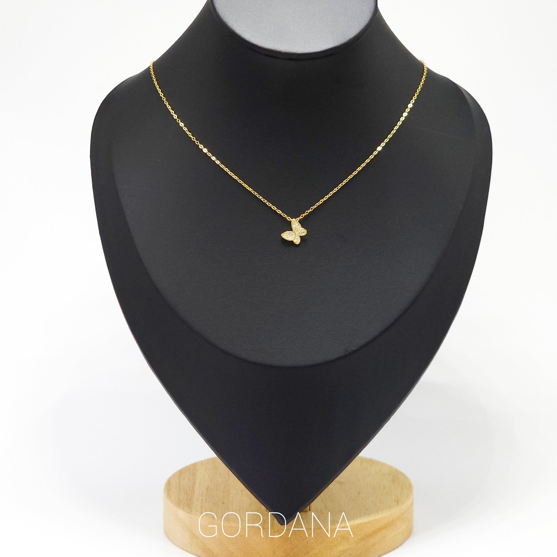 Gold plated butterfly pendant necklace on black display, elegant stainless steel jewelry, unisex fashion piece with.