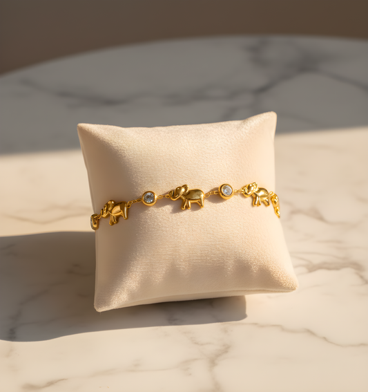 Gold bracelet with elephant charms on a beige cushion with a marble background