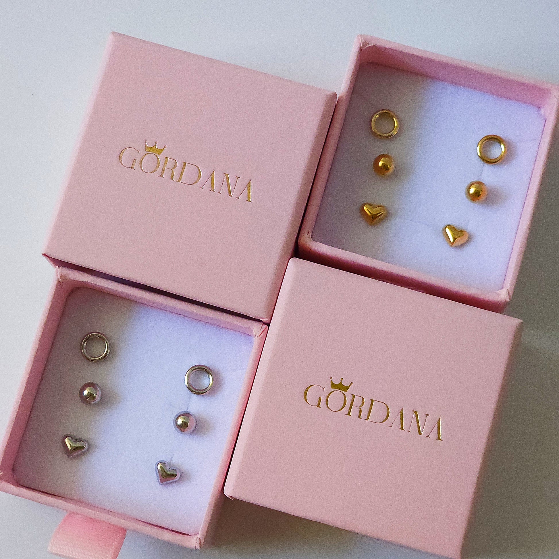Trio set of gold and silver stainless steel fashion earrings with gemstone accents in pink Gordana boxes.