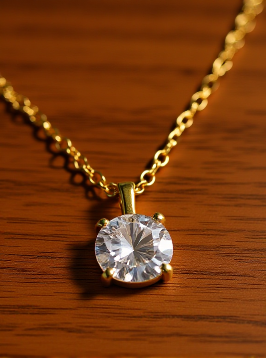 Gold necklace with a clear gemstone pendant on a wooden surface