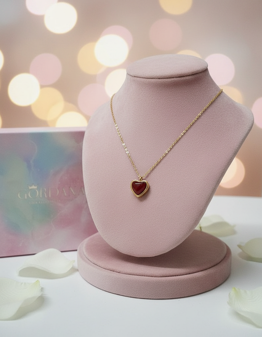 Necklace with a red agate heart pendant on a pink velvet stand against a blurred background