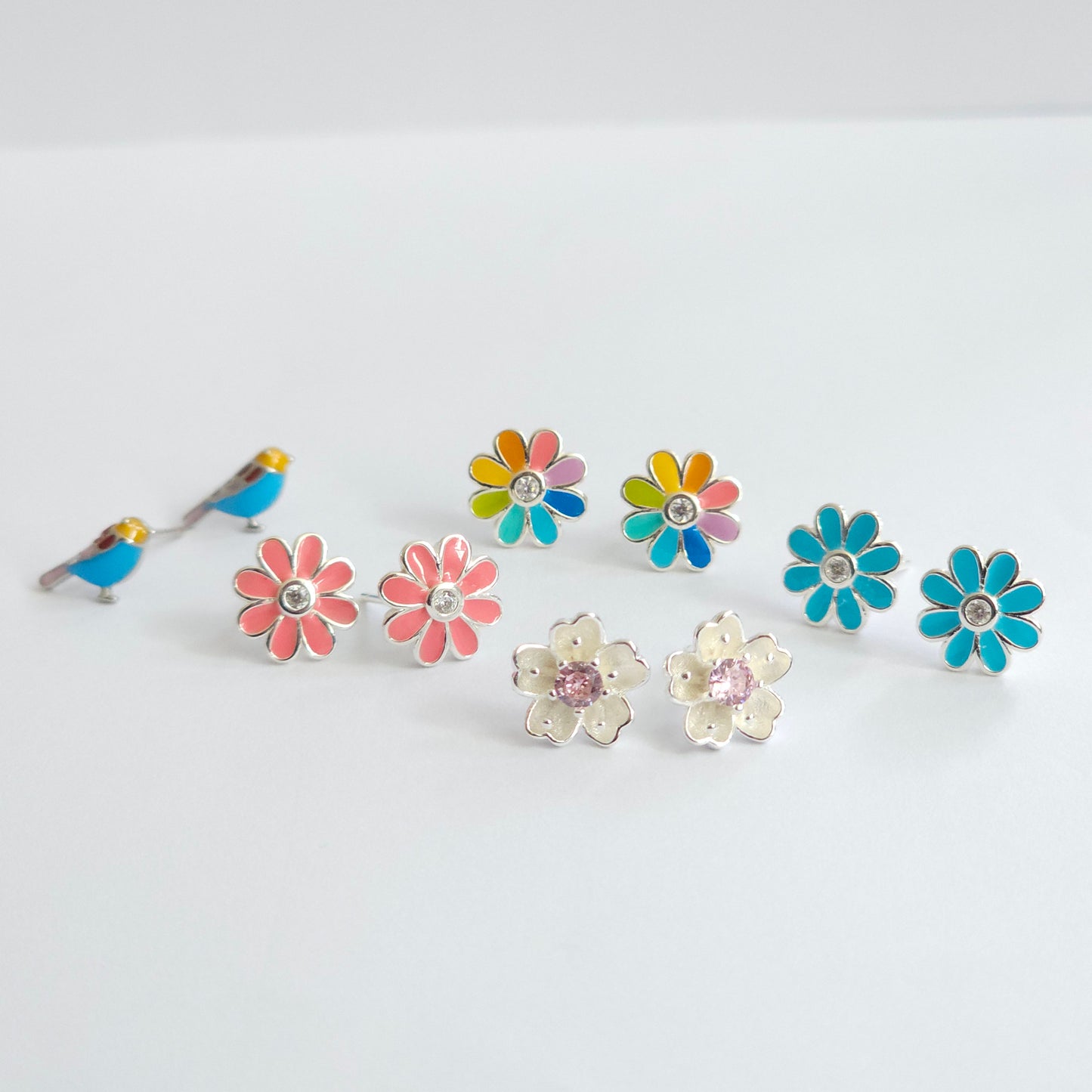 Silver jewelry stud earrings in butterfly, pink and blue daisy, and flower designs, stainless steel fashion jewelry.